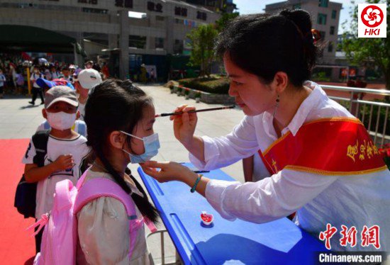 图为福州市高湖小学老师为一年级新生“点朱砂”启智。　张斌 摄
